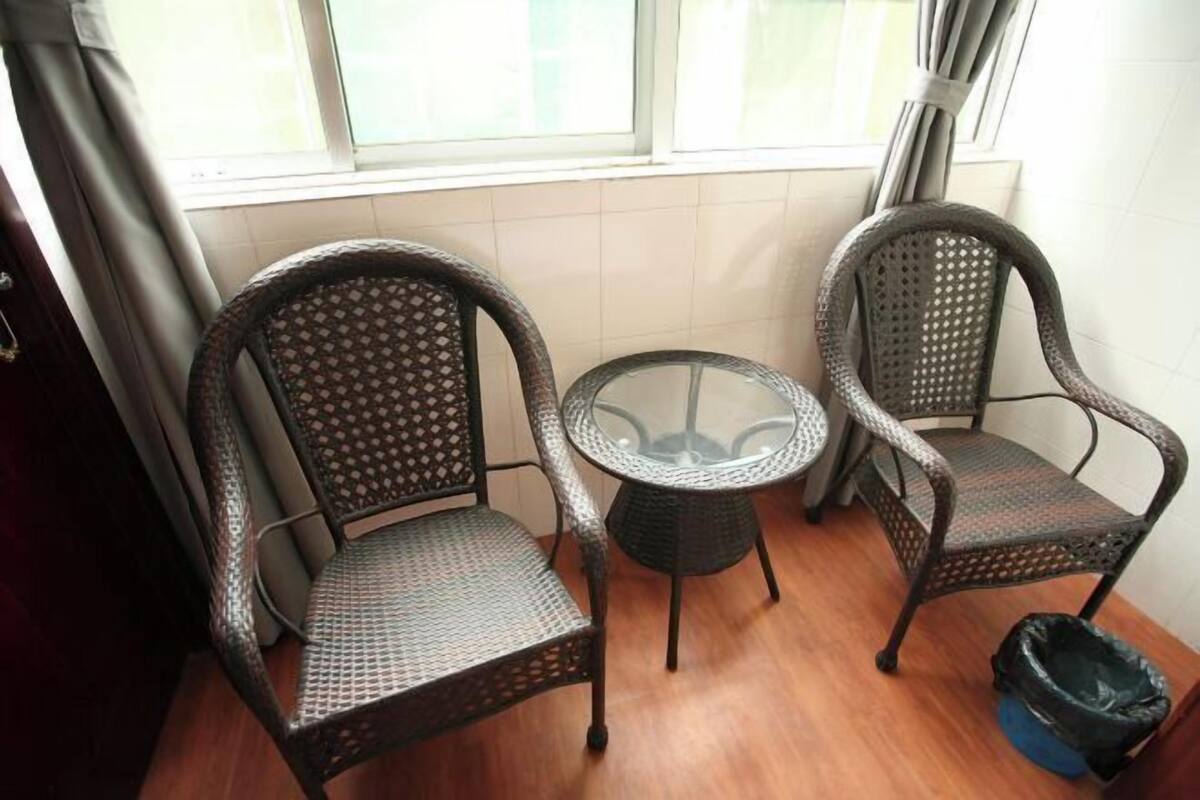 A corner room with two wicker chairs, a glass table, and a view through a window.