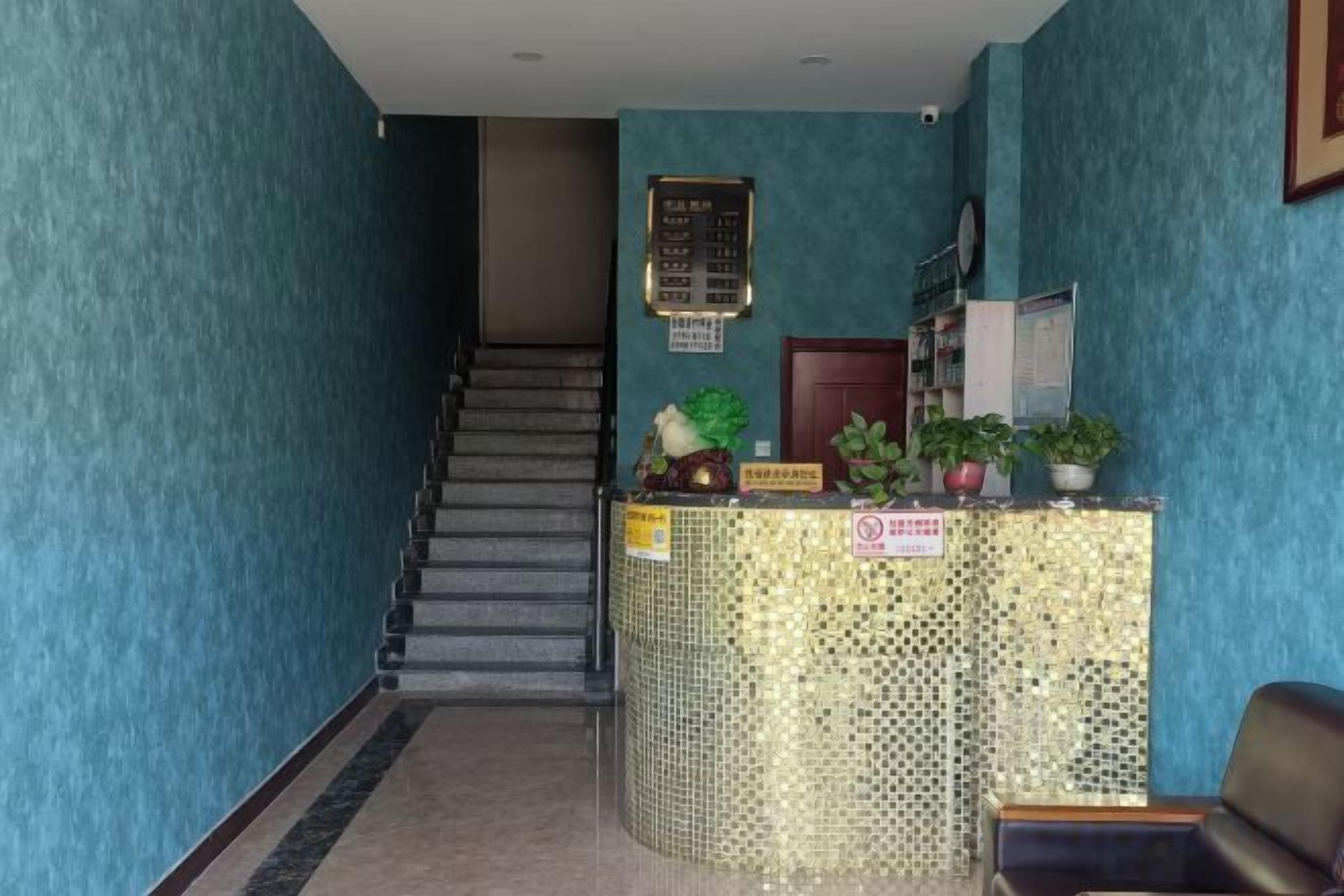 A reception area with a staircase, a reception desk, and a wall-mounted information board.