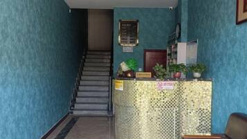 A reception area with a staircase, a reception desk, and a wall-mounted information board.