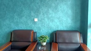 Two leather chairs with wooden armrests, a small table with a potted plant, and a teal textured wall. - Qiqi Hotel (Taiyuan Zhenwu Road Wanmaqi Square) (Taiyuan)