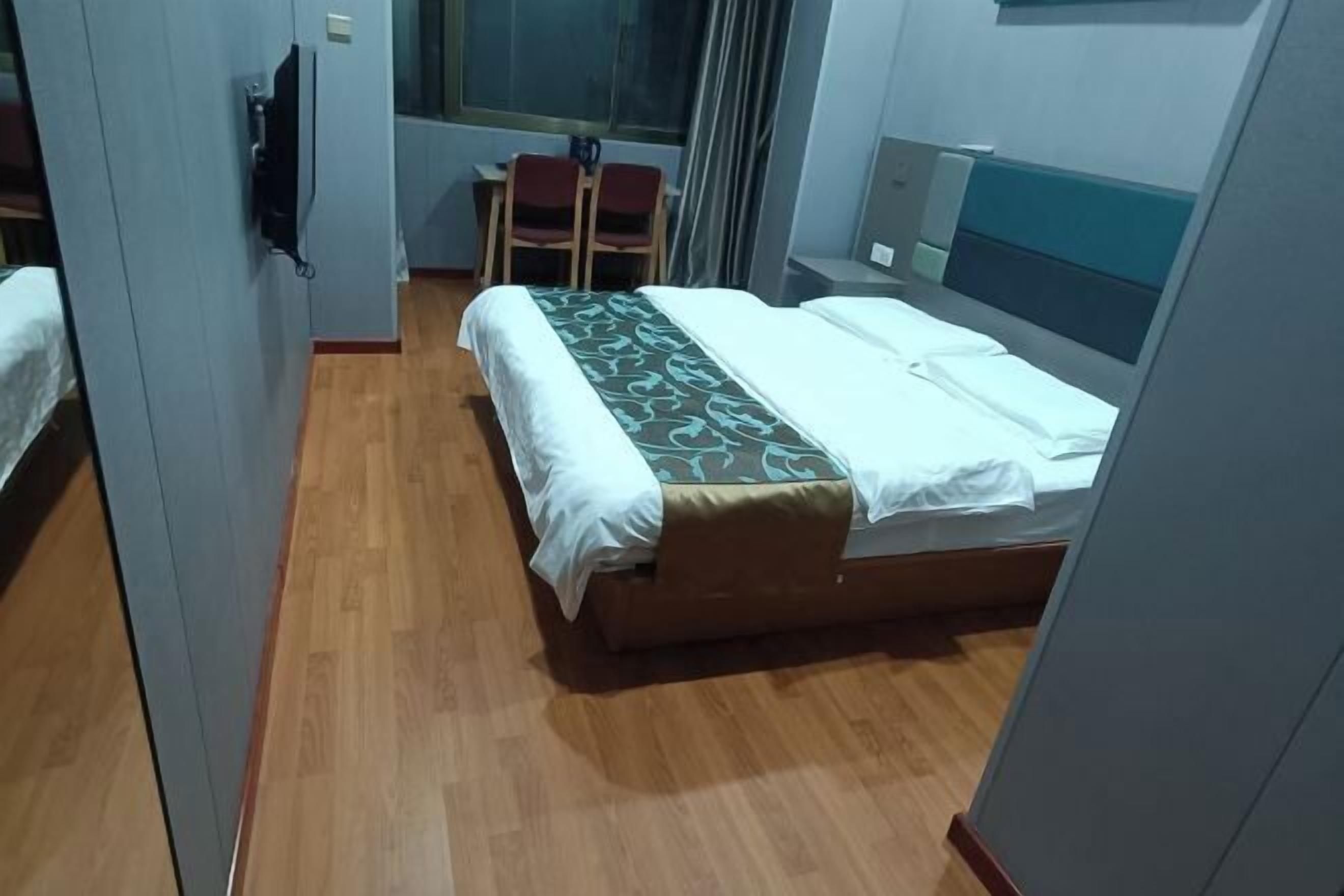 A hotel room with a bed, a desk, and a chair.