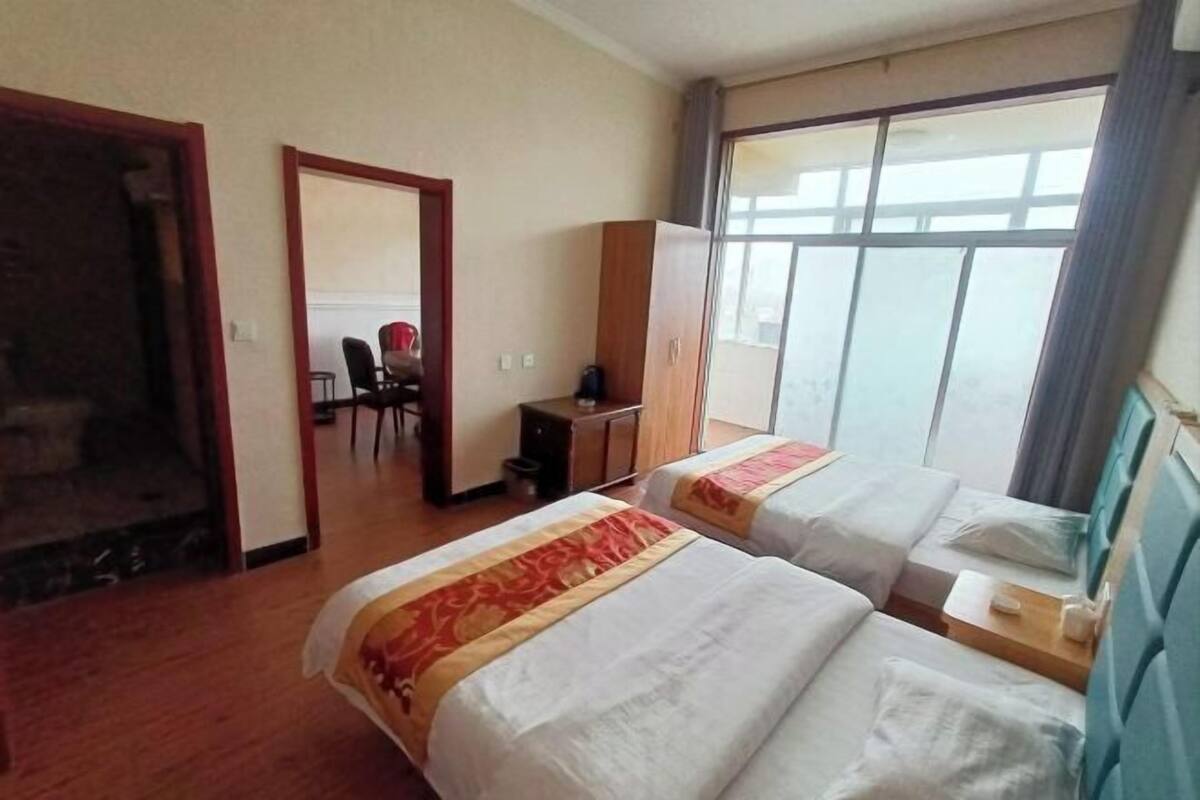 A hotel room with two beds, a desk, a chair, and a wardrobe.