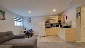 En kompakt opholdsstue med sofa, spisebord og tekøkken.