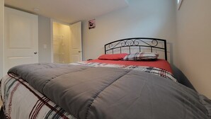 Et soveværelse med en seng, en loftlampe og en dør.