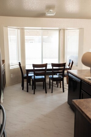 A kitchen with a dining table and chairs, large windows, and a dishwasher. - 4BR Yuma, AZ Home - 8 Beds, Free Tesla Charger, Near MCAS Yuma & Foothills (Yuma)