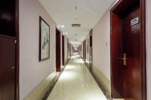 A hotel corridor with doors on both sides, a polished floor, and a sign on the right door. - Tashan Hotel Pujiang (Pujiang)