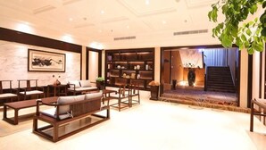 A spacious living area with a sofa set, a bookshelf, and a staircase leading to an upper floor. - Tashan Hotel Pujiang (Pujiang)