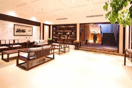 A spacious living area with a sofa set, a bookshelf, and a staircase leading to an upper floor.. Tashan Hotel Pujiang