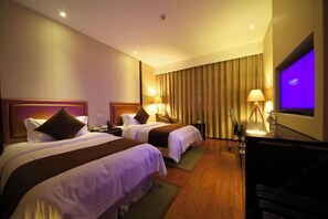 Une chambre d’hôtel avec deux lits, une télévision, un bureau et un rideau.