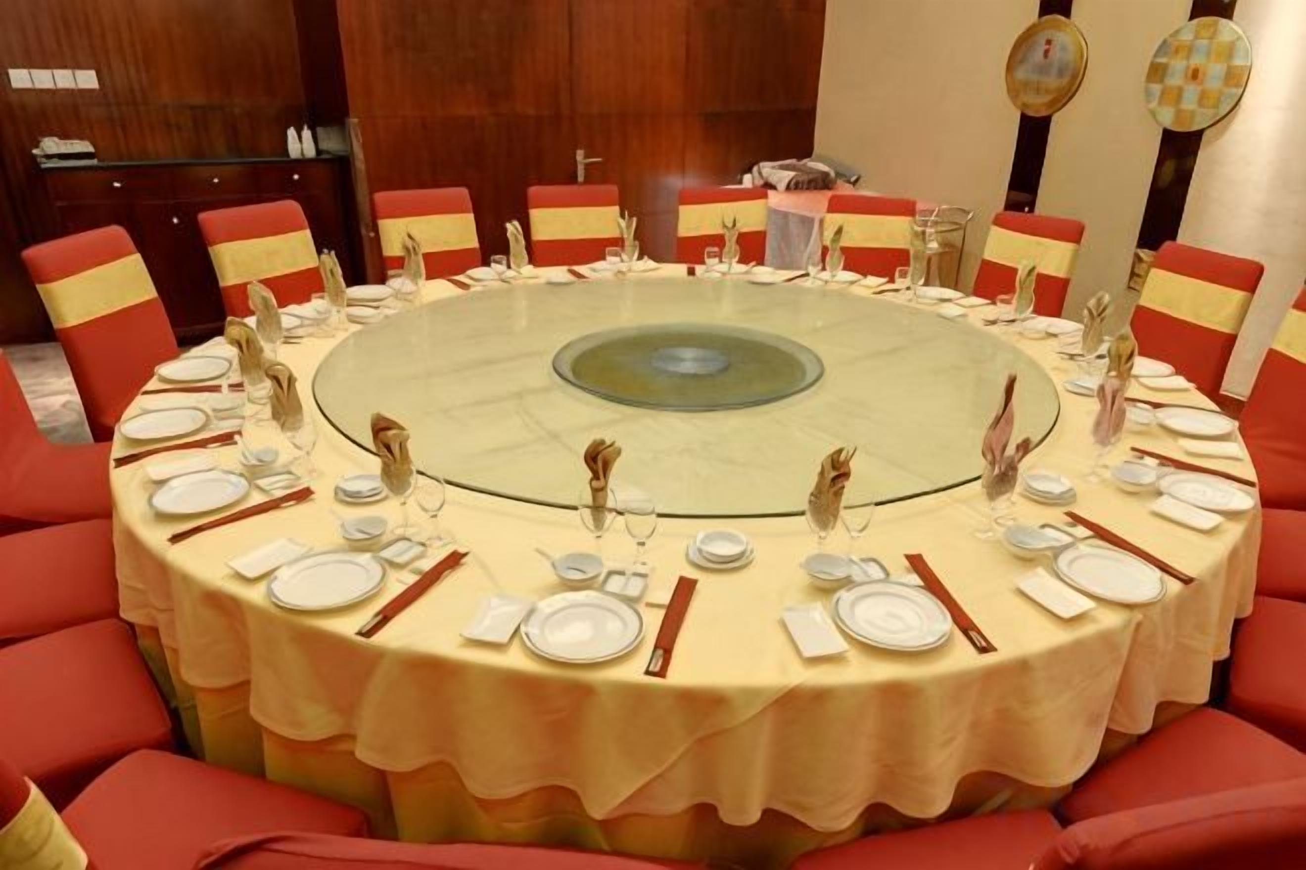 A round table set for a meal with chairs around it.