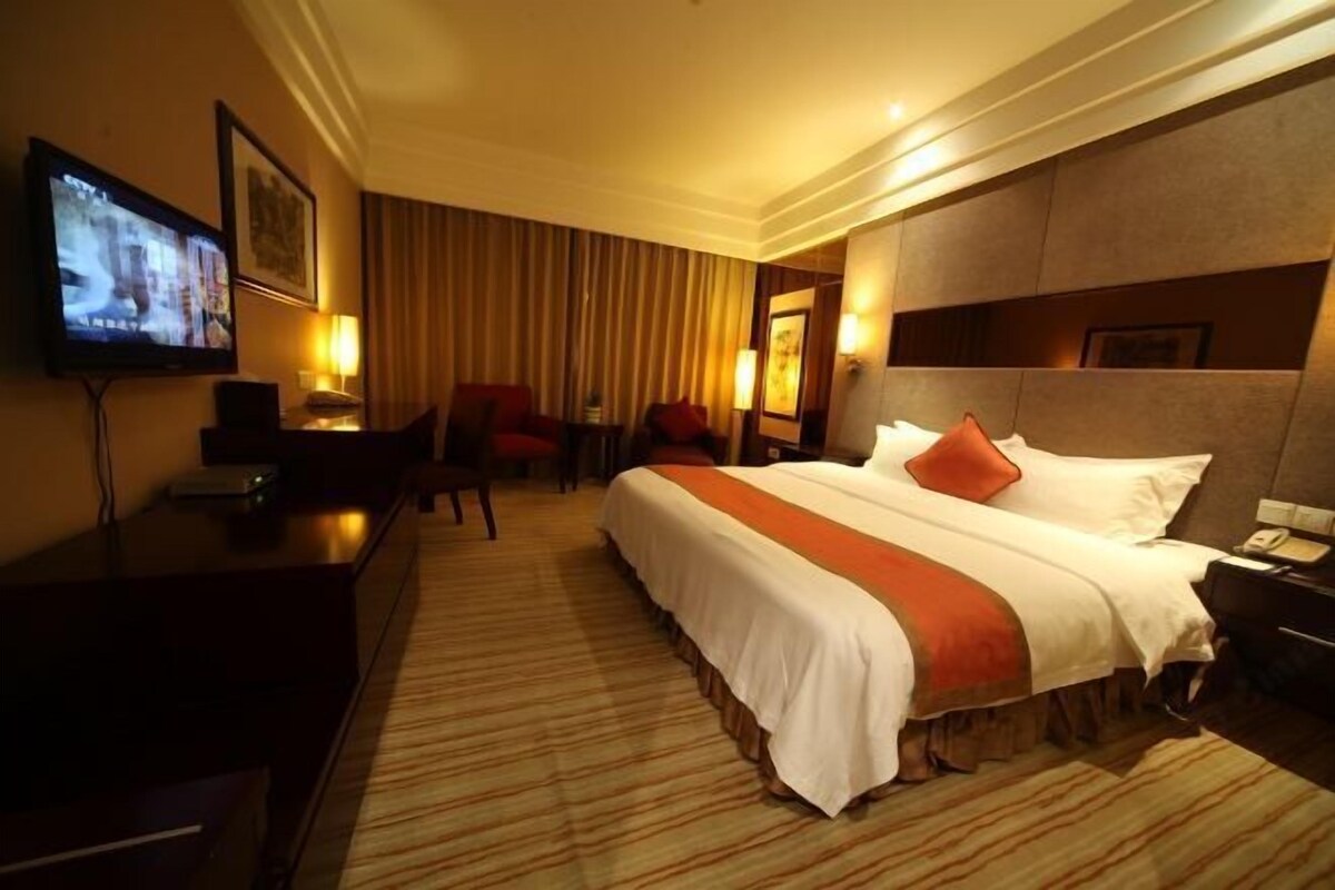 Ein Hotelzimmer mit einem großen Bett, einem Schreibtisch, einem Fernseher und einem Sessel.