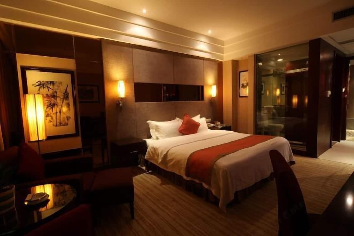 Une chambre d’hôtel avec un lit, des tables de chevet, un bureau et une chaise.