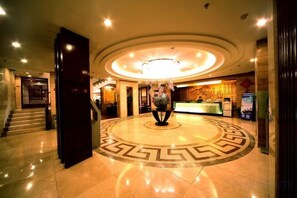 A hotel lobby with a central circular design, a reception desk, and a staircase. - Tashan Hotel Pujiang (Pujiang)