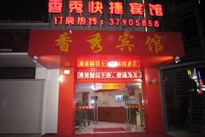 A hotel entrance with a red facade and a signboard displaying the hotel's name and contact number. - Xiangxiu Hostel (Shanghai)