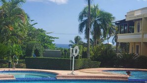 A swimming pool with a lifeguard stand, surrounded by palm trees and a clear sky.