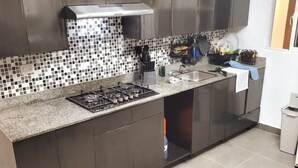Una cuina moderna amb fogó de gas, armaris foscos i una barra d'endollossos.