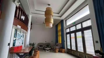 A hotel lobby with a reception desk, seating area, and large windows.