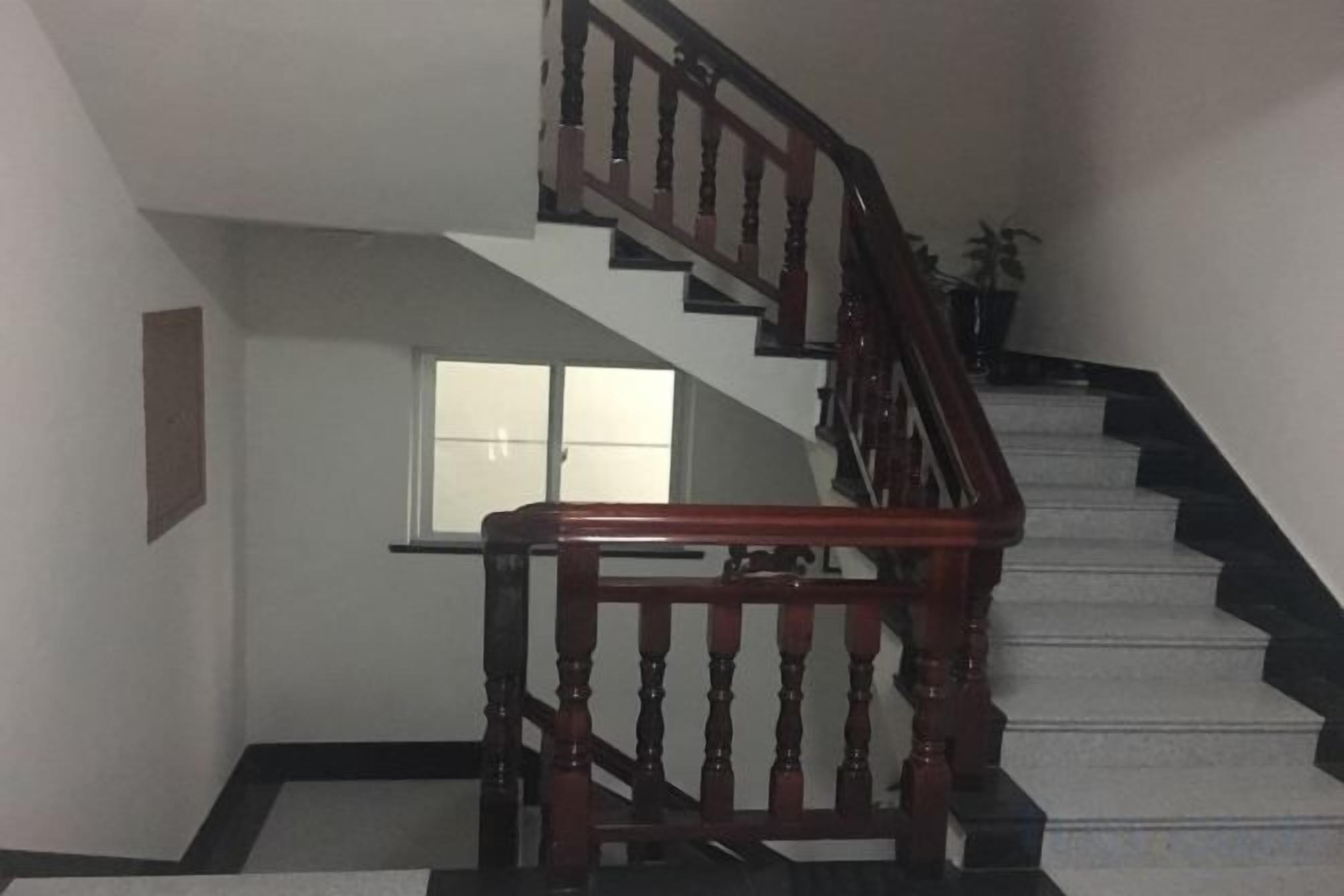 Una escalera con barandillas de madera y un rellano alfombrado.
