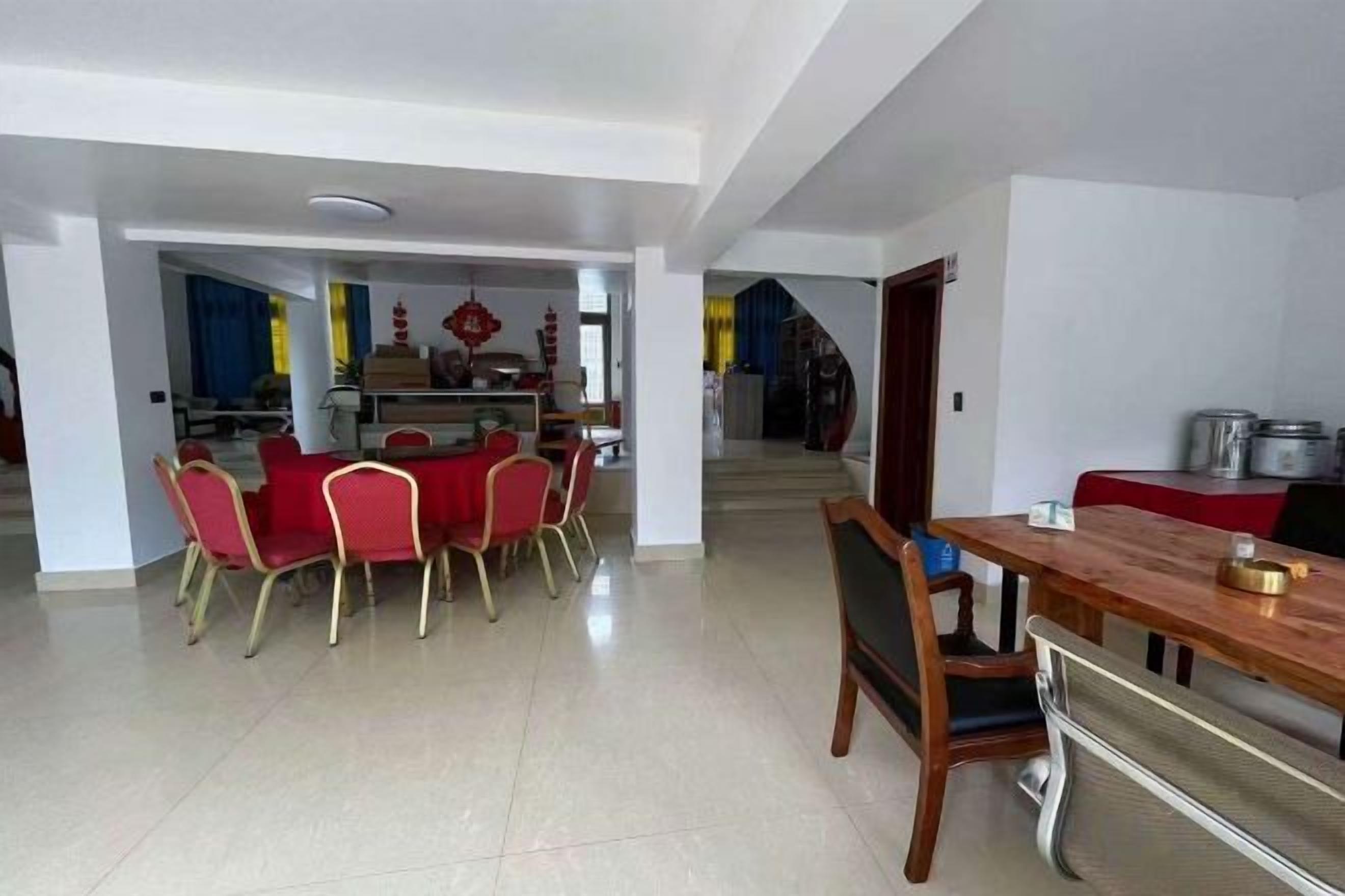 A dining area with a wooden table and red chairs, a kitchen area with pots and a stove, and a staircase leading to another level.
