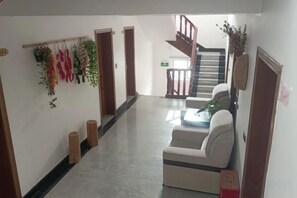 A hallway with a sofa, a staircase, and a wall-mounted plant arrangement. - Xinyue Inn (Yueqing)