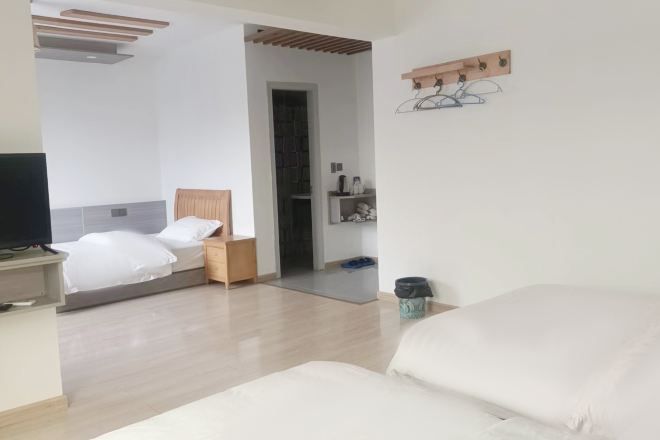 A modern hotel room with a bed, a desk, a television, and a small shelf with toiletries.