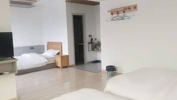 A modern hotel room with a bed, a desk, a television, and a small shelf with toiletries.