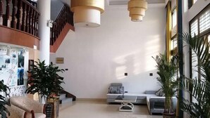 A spacious lobby with a staircase, a seating area with sofas, and large hanging lamps. - Xinyue Inn (Yueqing)