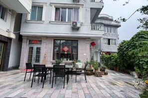 A courtyard with a dining table and chairs, surrounded by potted plants and a building with a traditional design. - Xinyue Inn (Yueqing)
