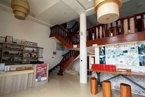 A hotel lobby with a reception desk, a staircase, and a bulletin board with maps. - Xinyue Inn (Yueqing)