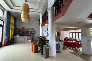 A spacious lobby with a reception desk, a dining area with red tables, and a staircase leading to an upper level. - Xinyue Inn (Yueqing)
