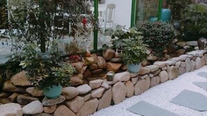 A garden area with potted plants, a stone wall, and a pebble pathway. - Xinyue Inn (Yueqing)