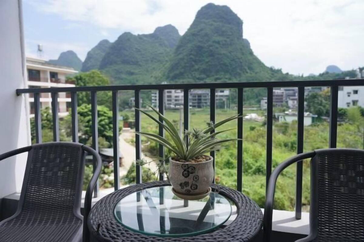 Un balcon avec deux fauteuils en osier, une table en verre et une plante en pot.