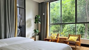 A hotel room with a large window, a bed, a chair, and a small table. - Linger House (Yangshuo)