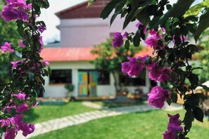 A building with a red roof, surrounded by a garden with purple flowers. - Linger House (Yangshuo)