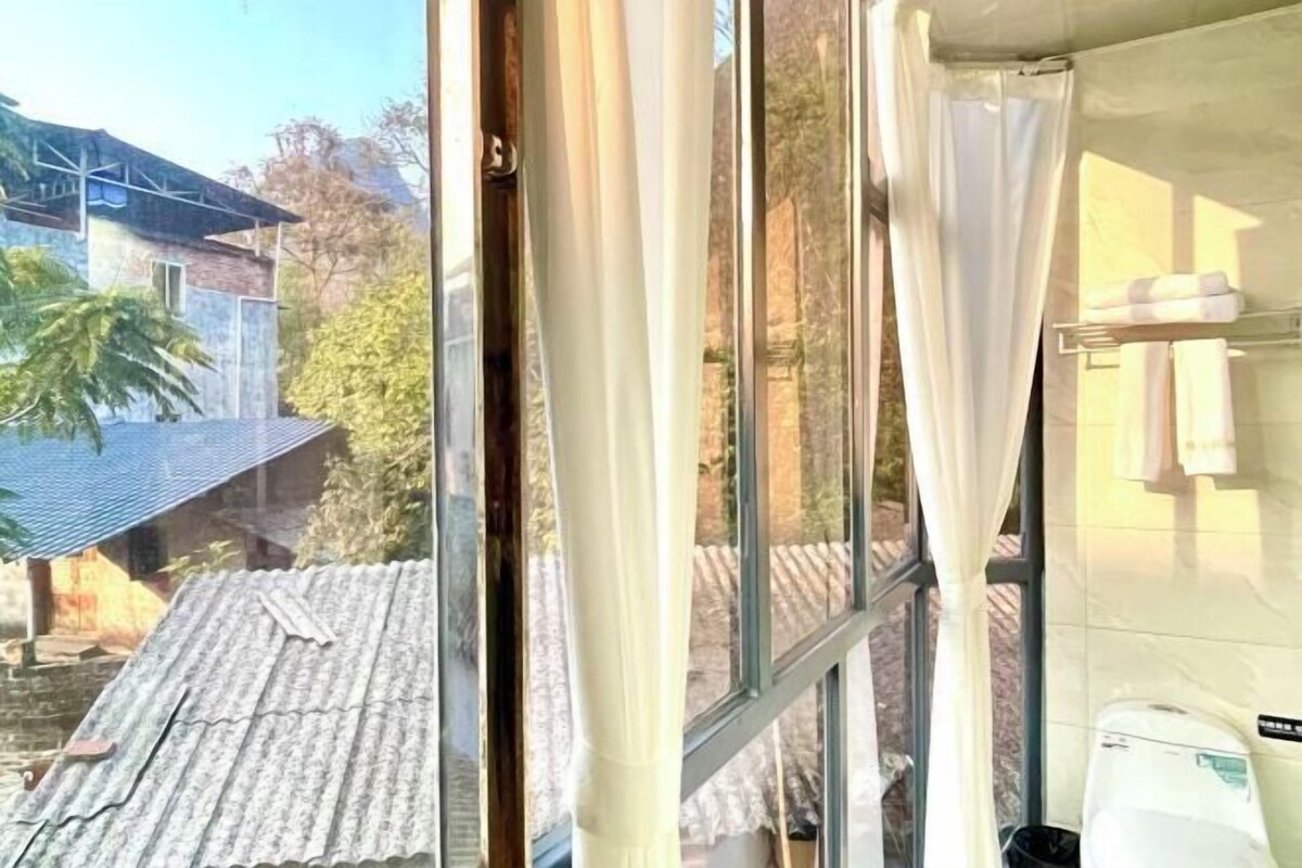 A bathroom with a window, a shower curtain, and a towel rack.