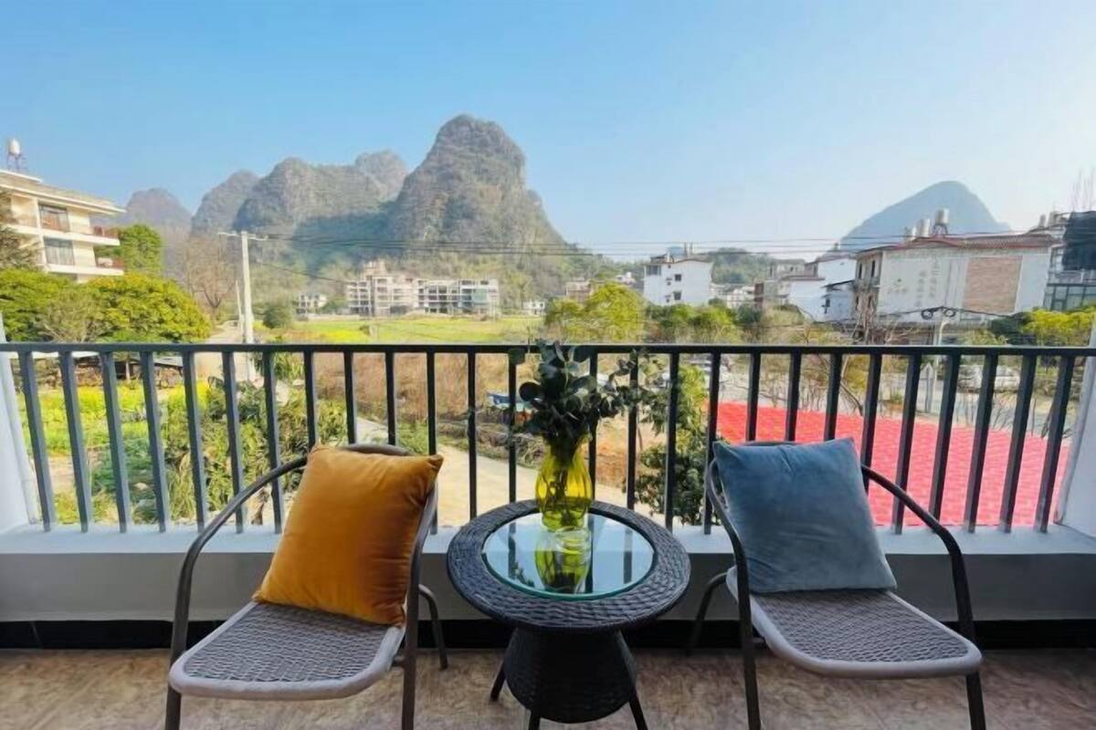 Un balcon avec deux chaises et une table, offrant une vue sur un paysage montagneux.