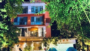 A multi-story hotel with outdoor seating and a tented area. - Linger House (Yangshuo)