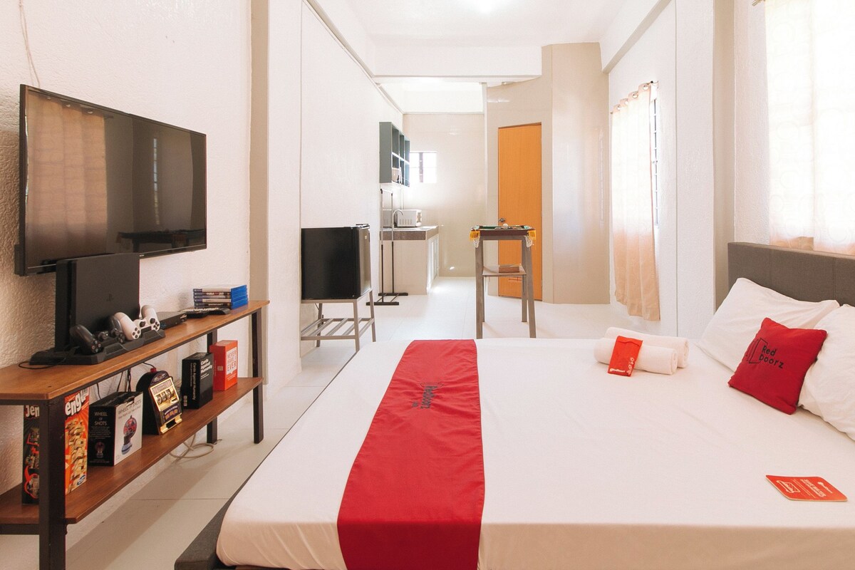 A hotel room with a bed, a TV, a desk, and a chair.