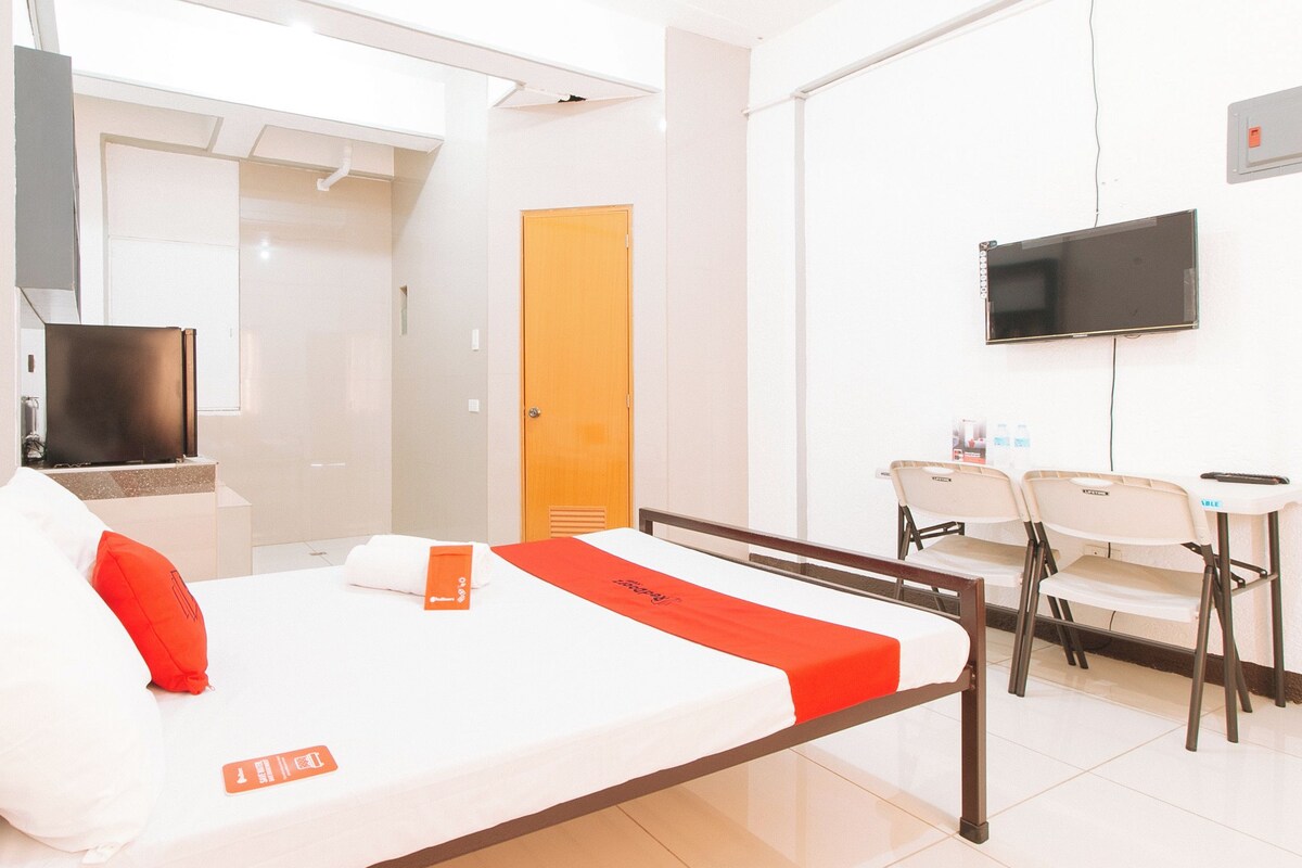 A hotel room with a bed, a TV, a desk, and a chair.