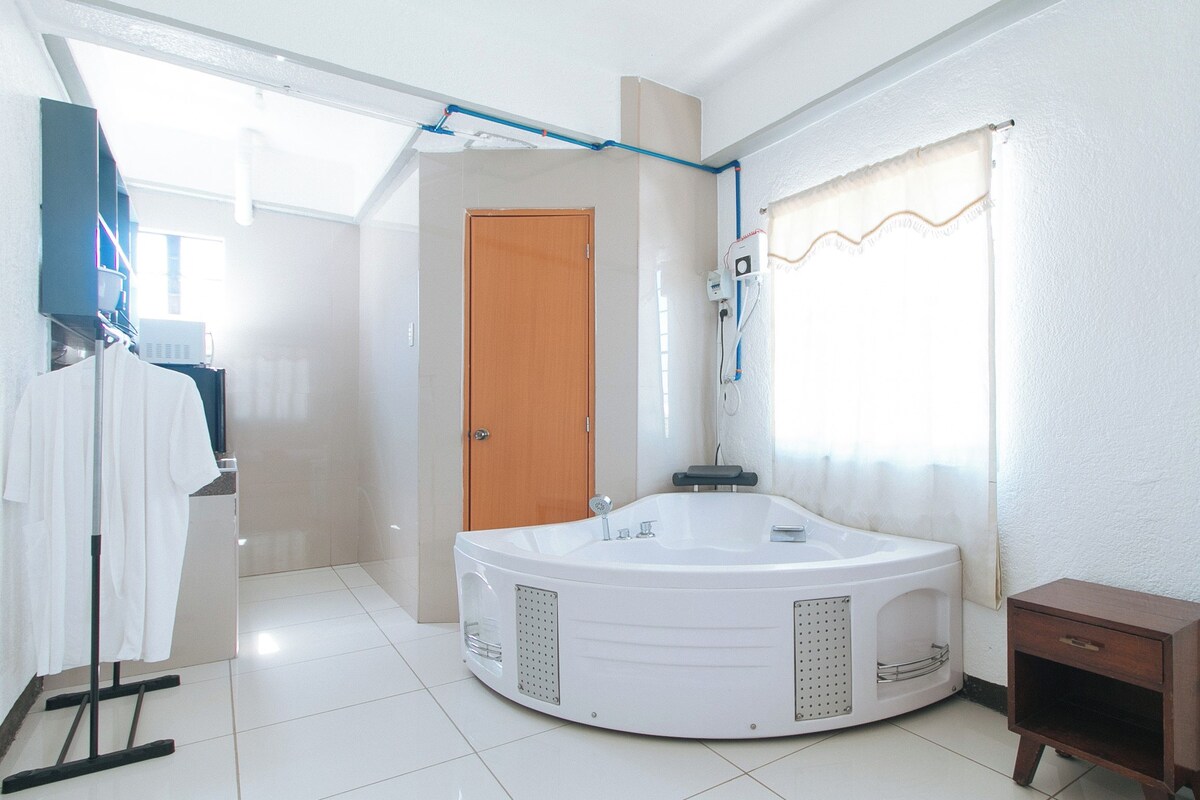A modern bathroom with a freestanding bathtub, a wooden door, and a towel rack.