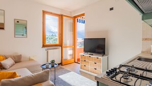 Une cuisine moderne équipée d’une cuisinière à gaz, d’un téléviseur et offrant une vue sur un paysage montagneux grâce à une grande fenêtre.