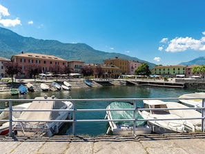 A waterfront with boats docked, buildings with red roofs, and mountains in the background. - Apartment Andy by Interhome (Colico)