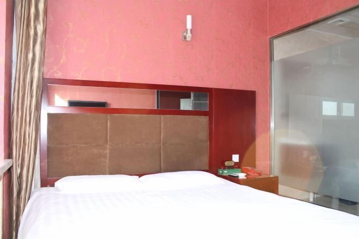 A hotel room with a large bed, a wooden headboard, a nightstand, and a sliding glass door.