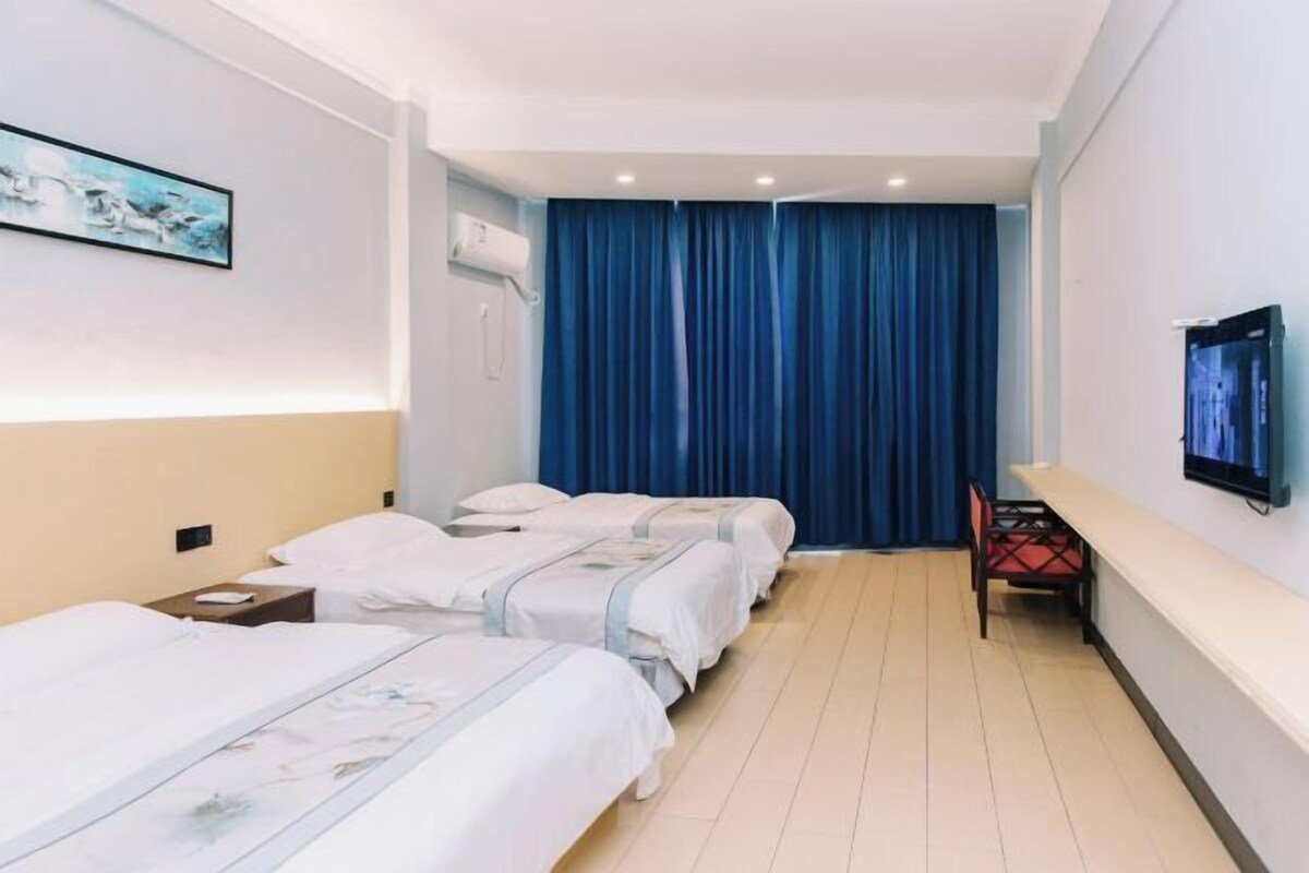 A hotel room with two beds, a desk, a chair, a TV, and a painting on the wall.