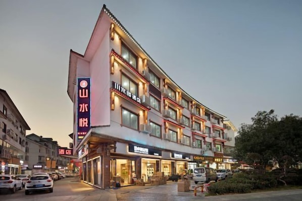 A multi-story hotel with a prominent sign on the left side, multiple balconies, and various storefronts on the ground floor.
