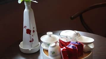 A dining table with a white teapot, cups, and a plate with red packets.