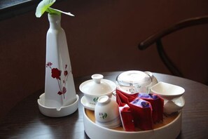 A dining table with a white teapot, cups, and a plate with red packets.