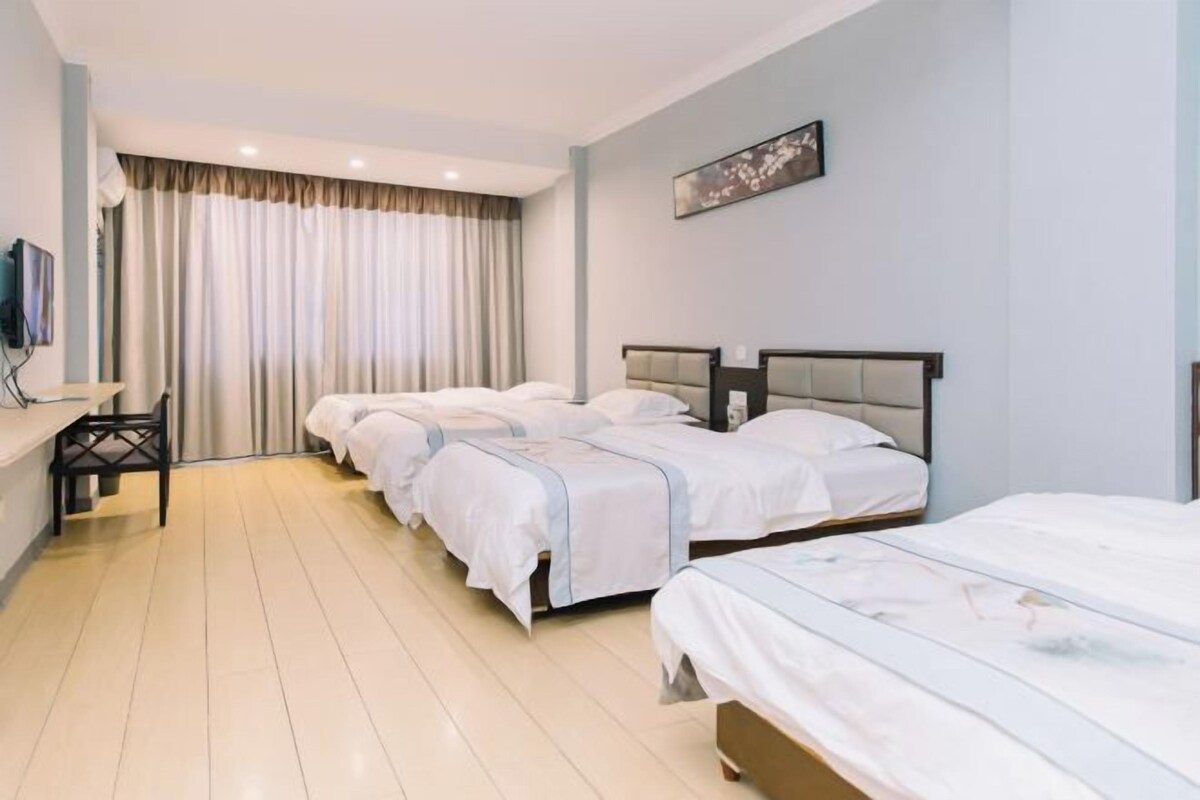 A hotel room with three beds, a desk, and a chair.