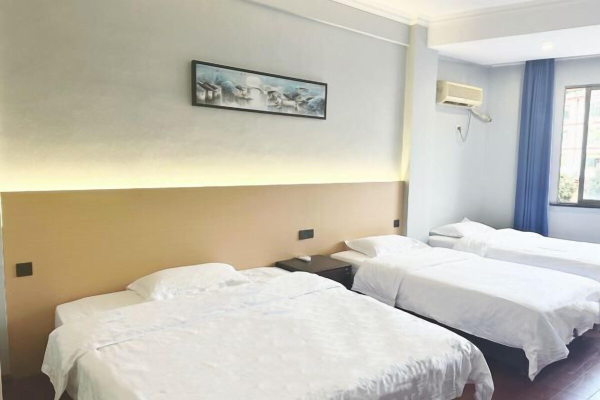 Habitación de hotel con dos camas, un cuadro en la pared, un equipo de aire acondicionado y una ventana con cortinas.