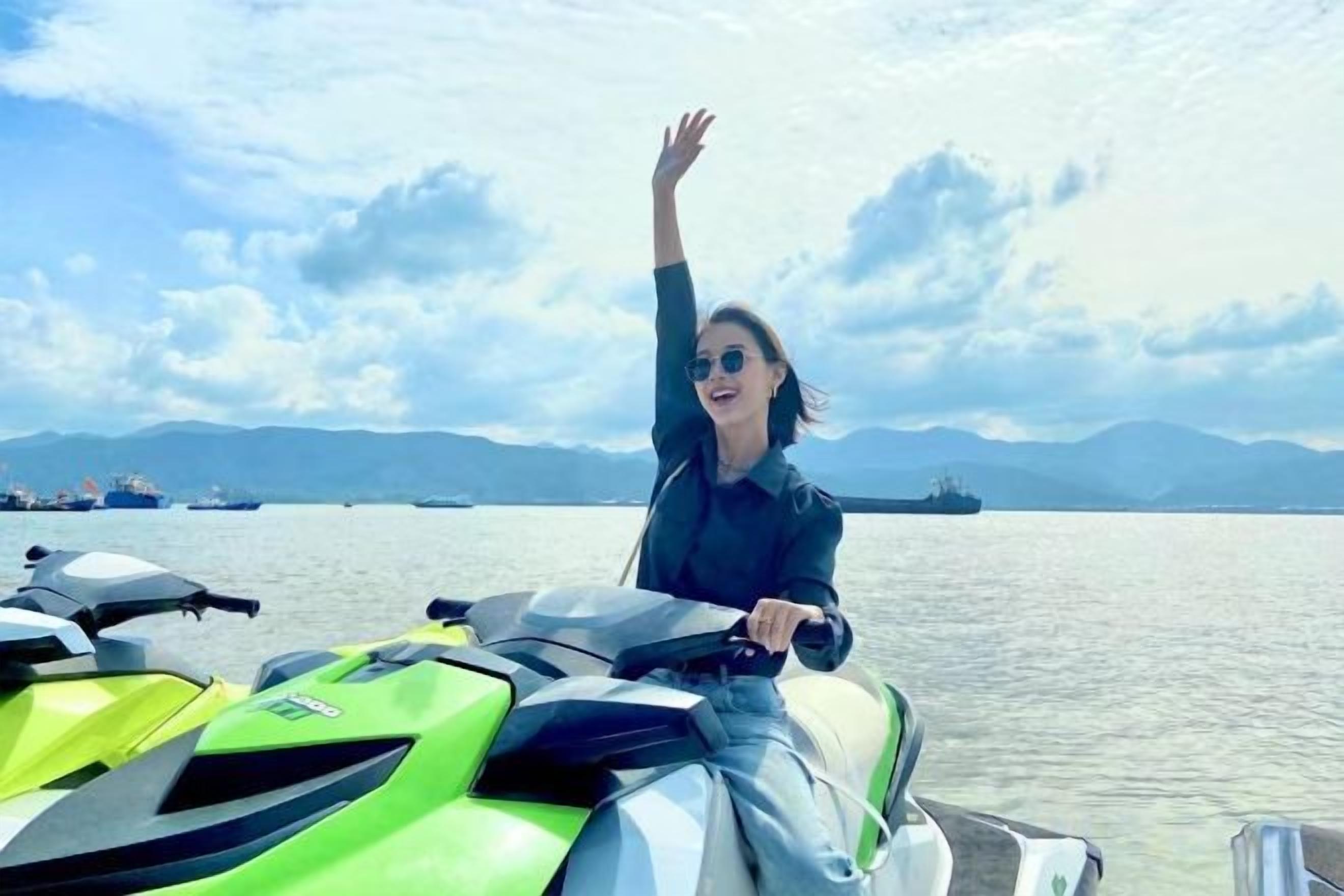 Una persona en un jet ski verde y blanco, con una masa de agua y montañas distantes al fondo.